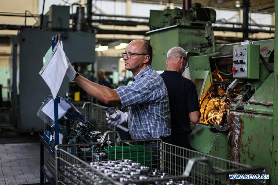 Workers inspecting precision-machined bearing components on a factory floor.